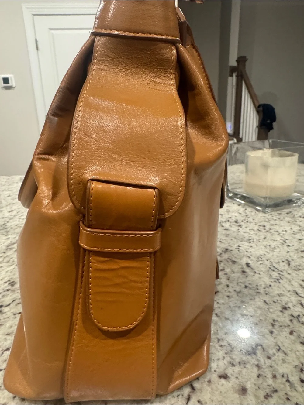 The Find Classic Tan Leather Weekender Travel Bag with Gold Hardware Buckle.